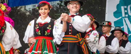 Menschen in bunten Gewändern tanzen auf einer Bühne.